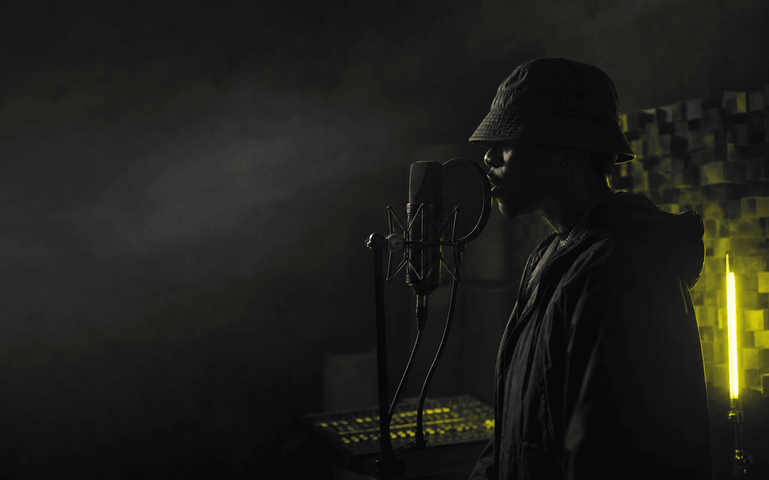 Rap artist recording vocals in a dark studio